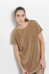 Vestido corto tipo remerón de lycra con acabado brillante color dorado. Presenta cuello redondo, mangas cortas y detalle de hombreras decoradas con tachas y cadenas metálicas.