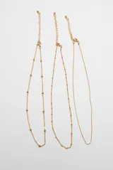 Set de tres collares dorados de cadena fina con pequeñas cuentas esféricas espaciadas y cierre de mosquetón con cadena de alargue.