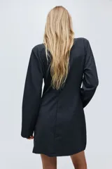 Vestido corto de punto color gris oscuro, con diseño cruzado, escote en V y aplicación de tiras de strass colgantes en el frente. Cuenta con mangas largas y hombreras.