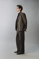 Pantalón relaxed fit de traje color marrón oscuro, confeccionado en tejido con mezcla de algodón. Cuenta con bolsillos frontales, bolsillos traseros de doble vivo con botón y efecto lavado. Cierre frontal con cremallera y botón.
