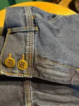 Bombacha de campo Sierra Mora confeccionada en denim de algodón, de tiro medio, con bolsillos y bordado de un caballo en el bolsillo trasero. Cuenta con pretina con botones, cierre delantero y puños ajustables con botones.