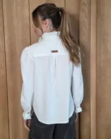 Camisa de manga larga con estampado de cuadros en tonos marrones y azules. Presenta cuello alto con volados, cierre frontal con botones y puños con volados.