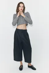 Pantalón de tiro medio con diseño balloon de pierna ancha. Presenta pliegues frontales, costuras horizontales marcadas en las piernas, bolsillos laterales y cierre frontal con cremallera y botón.