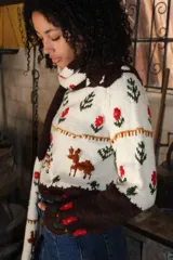 Sweater de punto jersey tejido a mano en 100% lana merino, de diseño multicolor con motivos de ciervos, árboles y flores bordados. Presenta cuello alto y puños en color marrón oscuro.