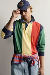 Polo de manga larga con diseño de rayas verticales anchas en colores amarillo, verde, rojo, azul marino y celeste. Cuenta con cuello camisero de denim y cierre frontal parcial con botones ocultos bajo solapa.