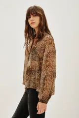 Camisa de manga larga con cuello camisero y cierre frontal de botones, confeccionada en tejido fluido con estampado animal print de leopardo.
