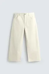 Pantalón relaxed fit de color crudo, confeccionado en tejido de algodón con estructura diagonal, diseño de cinco bolsillos y cierre frontal con cremallera y botón.