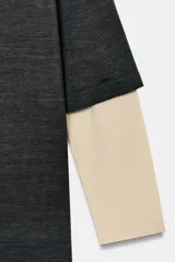 Jersey de cuello redondo y manga larga con diseño de doble capa, combinando un cuerpo en tono gris oscuro con mangas en tono beige.