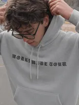 Canguro de felpa gris melange con capucha, manga larga y estampa trasera de estilo rockero con tipografía y calavera.