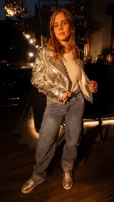 Chaqueta corta plateada de simil cuero con solapas y detalles de tachas rosadas.