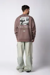 Buzo de cuello redondo y corte oversize, confeccionado en frisa suave. Presenta un diseño minimalista en color negro con un pequeño logo ovalado en el centro del pecho y una estampa sutil en el lateral inferior derecho.