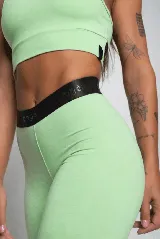 Calza deportiva color verde claro, de tiro alto y corte ajustado. Presenta cintura elástica con logo en relieve.