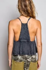 Top camisero negro de algodón sin mangas, con escote cuadrado y tirantes ajustables. Presenta bordados florales en el corpiño y en el bajo, corte imperio fruncido y silueta fluida.