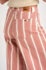 Jean wide leg de tiro alto con diseño de rayas verticales en tonos rosado y blanco, con bolsillos laterales y traseros, y cierre frontal con botón y cremallera.