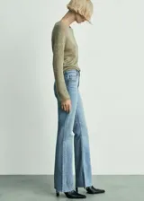 Jeans de denim de tiro medio y corte flare con diseño campana, cinco bolsillos, trabillas para cinturón y bajo deshilachado.