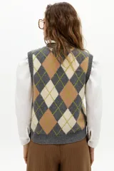 Chaleco de punto color gris con estampado de rombos (argyle) en beige y verde lima. Tiene escote en V, botones frontales y terminaciones de rib.