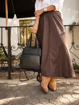 Mochila versátil convertible en cartera, color beige con detalles en marrón. Cuenta con doble asa superior, correas ajustables y desmontables, bolsillo frontal con cierre y compartimento principal amplio.