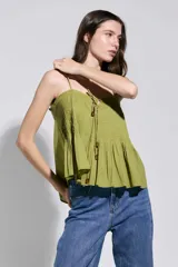 Top verde pistacho con tirantes finos, diseño fruncido en el pecho y detalle de cordones con cuentas en la parte frontal, con corte evasé.