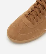 Championes de mujer estilo chuteira, color verde oscuro con detalles en blanco y suela de goma color caramelo. Presentan un diseño de corte bajo con cordones y un logo lateral en forma de arco.