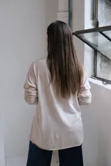Remera de algodón color beige, con cuello en V, mangas largas con costuras caídas y ruedo con detalle de costura horizontal.