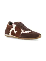 Championes de diseño urbano con paneles combinados en gamuza marrón y pelo sintético con estampado de vaca en tonos marrón y blanco. Presenta cierre con cordones al tono y suela de goma plana.