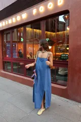 Vestido largo de denim azul, de corte recto y holgado, con tirantes finos y tajo lateral en la parte inferior.