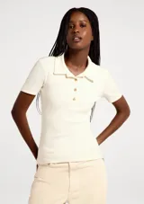 Remera polo de manga corta, color blanco, de corte ajustado con cuello camisero y cartera de tres botones frontales.