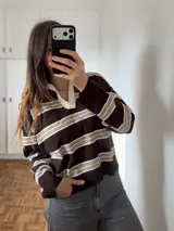 Sweater de punto a rayas horizontales en tonos marrón, beige y blanco, con cuello polo blanco en contraste y mangas largas.