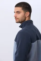 Buzo de polar bicolor azul marino y verde con medio cierre y bolsillos laterales con cierre.