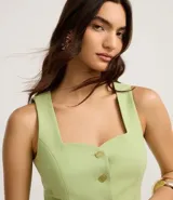 Chaleco sastrero color verde lima, con escote cuadrado y detalle de corazón en el busto, abotonado al frente con botones dorados. Presenta pinzas delanteras y bolsillos falsos.