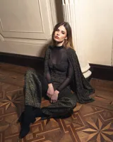 Top de punto negro con escote en V y bretel decorativo que se ata en el cuello.