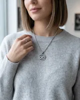 Dije circular de plata 925 con el símbolo de infinito calado en el centro.