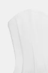 Top tipo corset de escote corazón y hombros descubiertos, con varillas interiores para estructura. Presenta cierre frontal con ganchos metálicos y ajuste en la espalda mediante cordones cruzados.