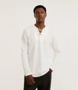 Bata masculina de manga larga en color blanco, confeccionada en tejido texturizado de algodón y poliéster. Presenta cuello en V con detalle de cordones cruzados y lazo ajustable.