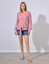 Blusa estampada con cuello a la base, escote en V y aplique de puntilla. Terminación de ruedo con nudo.