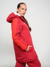 Parka larga de abrigo Umbro del Club Nacional de Football, color rojo con detalles en naranja en las mangas. Cuenta con capucha, cierre frontal con botones a presión y escudo del club bordado en el pecho.