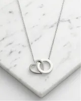 Collar de acero con cadena fina y dos dijes entrelazados, uno en forma de corazón y otro circular.