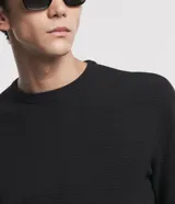 Suéter negro de tejido de punto maquinetado con cuello redondo y manga larga.