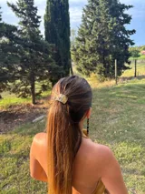 Accesorio para el cabello tipo colita con aplique metálico de diseño rectangular y acabado texturizado en color dorado.