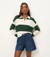 Bermuda de jeans azul oscuro, con trabillas en la cintura, bolsillos laterales y traseros, y cierre de botón y cremallera.