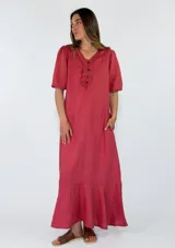 Vestido largo de lino color rojo, con cuello en V decorado con volados, mangas cortas abullonadas, bolsillos laterales y falda con volado en el ruedo.