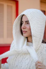 Sweater de lana color blanco con diseño de trenzas y capucha integrada con lazos ajustables.
