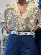 Cinto blanco de cuero sintético con tachas plateadas y hebilla metálica plateada.