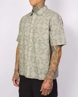 Camisa de manga corta color verde con estampado geométrico, cierre frontal con botones y un bolsillo en el pecho.
