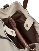 Cartera tipo shopper y bandolera color crema con asas cortas y correa ajustable de color marrón, herrajes metálicos dorados y detalle de logotipo en la parte frontal.