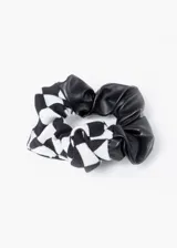 Scrunchie con una mitad de tela de cuero sintético negro y la otra mitad de tela con estampado a cuadros blancos y negros.