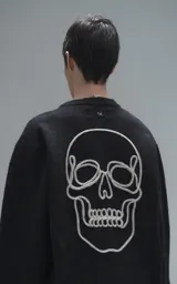 Sweater de cuello redondo color negro, con diseño de calavera bordado en relieve en color blanco en la espalda. Presenta terminaciones en punto rib en cuello, puños y ruedo, con un calce relajado y oversize.