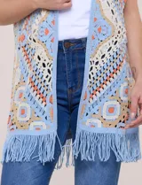Cardigan tejido al crochet de color celeste, beige y naranja, con diseño geométrico y flecos en el ruedo.