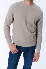 Buzo de punto en color taupe, con cuello redondo y textura acanalada. Presenta mangas largas y puños ajustados, ofreciendo un diseño clásico y versátil.