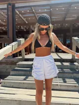 Conjunto de bikini negro con corpiño triangular con argolla metálica y bombacha colaless con tiras para atar y argollas en los costados.